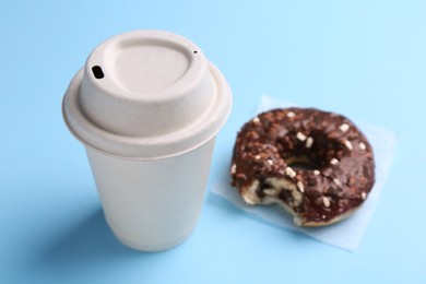 Cup of hot drink and tasty donut on light blue background