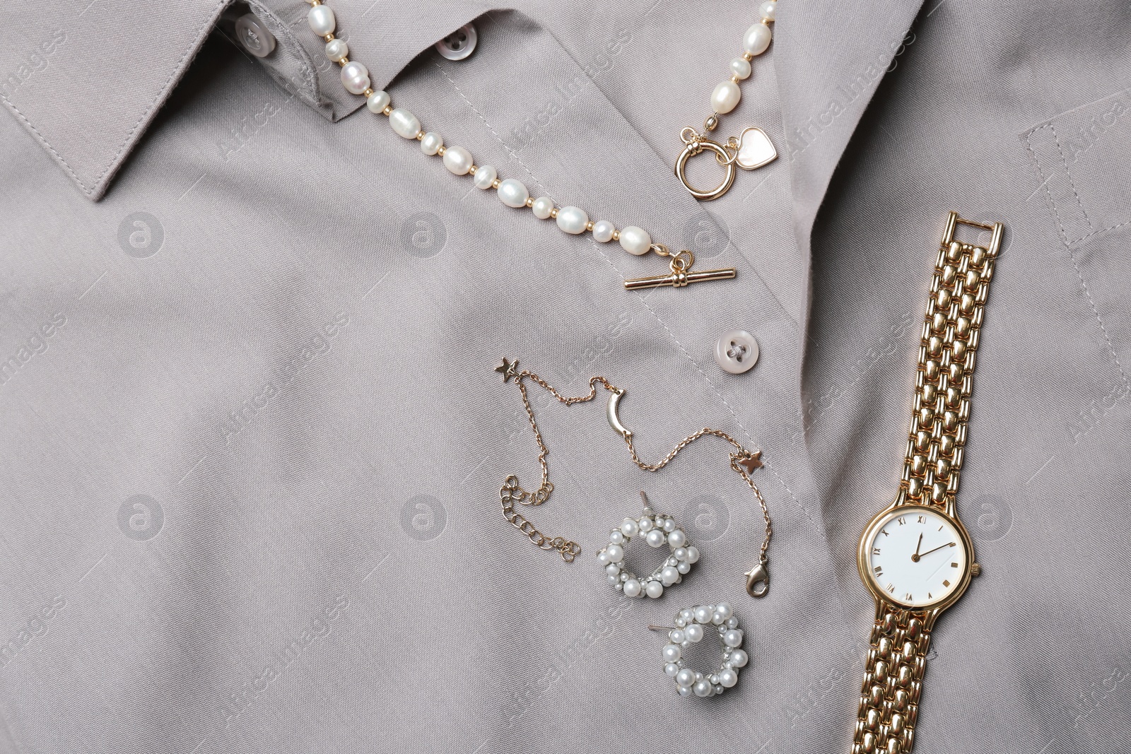 Photo of Different elegant jewelry on grey shirt, flat lay. Space for text