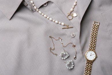 Photo of Different elegant jewelry on grey shirt, flat lay. Space for text