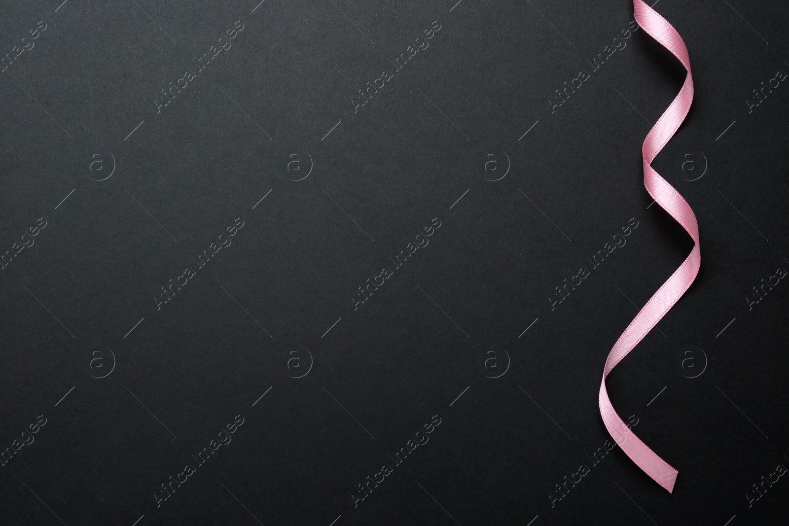 Photo of Beautiful pink ribbon on black background, top view. Space for text