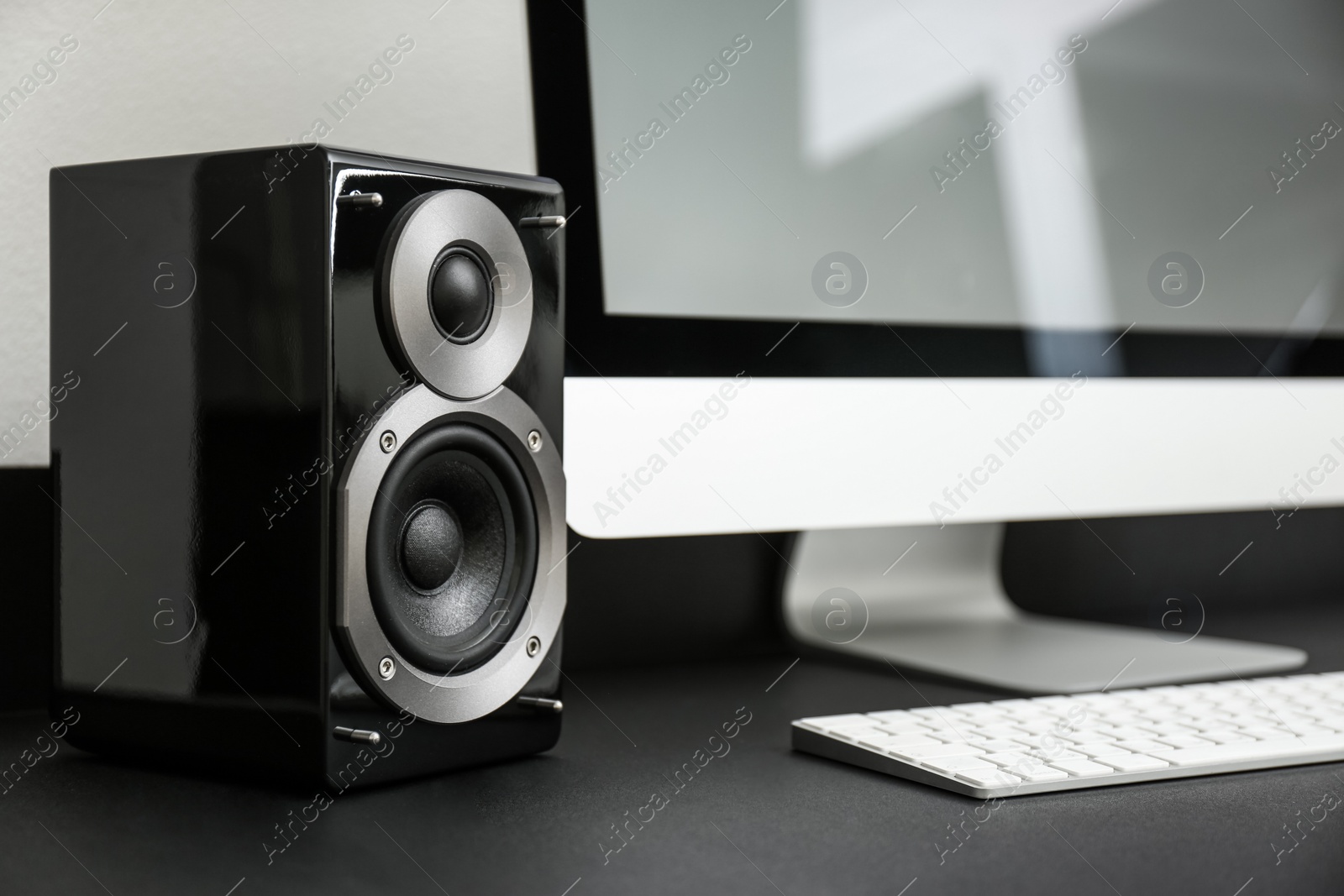 Photo of Modern audio speaker and computer on table indoors
