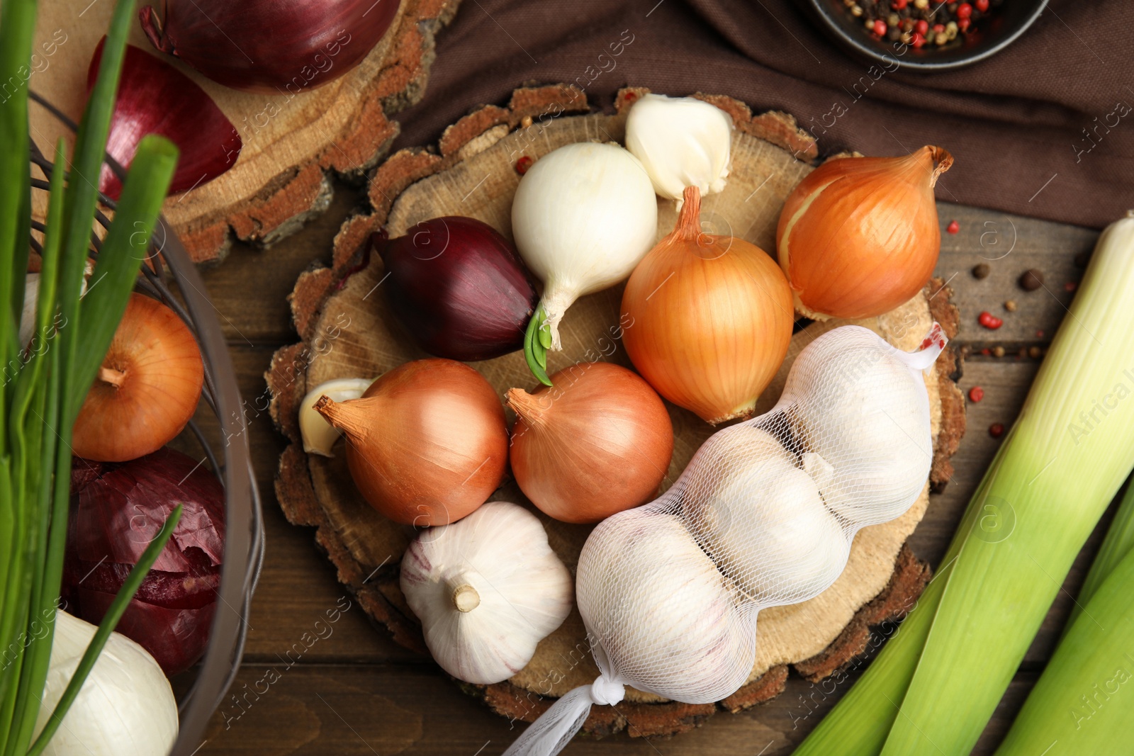 Photo of Fresh onion bulbs, leeks and garlic on wooden table, flat lay