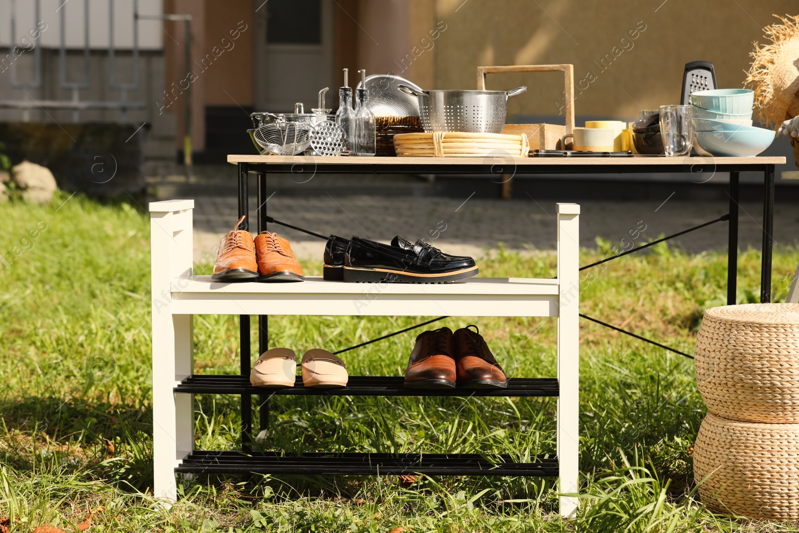 Photo of Shoe rack and table with many different items on garage sale in yard
