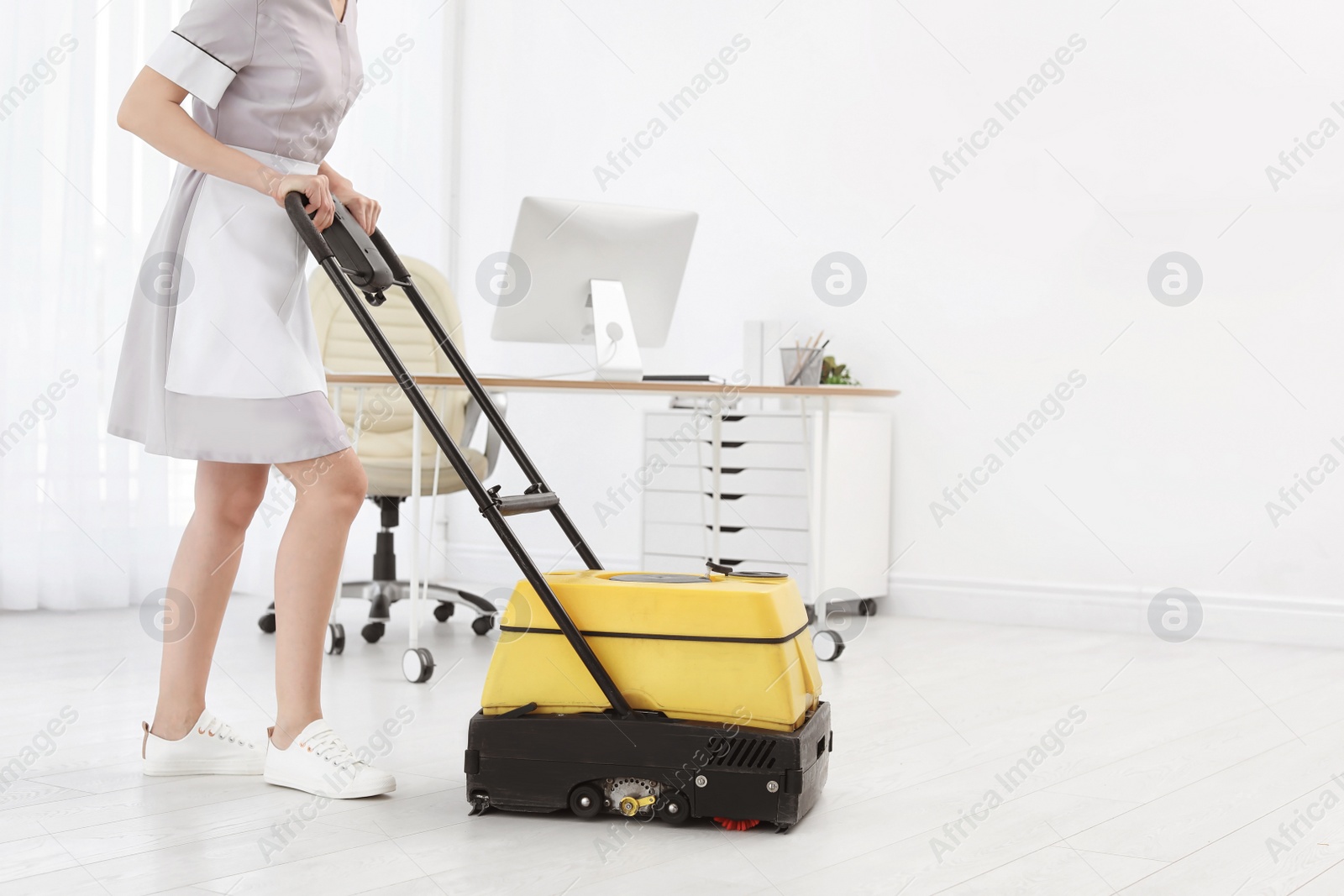 Photo of Female worker with floor cleaning machine indoors