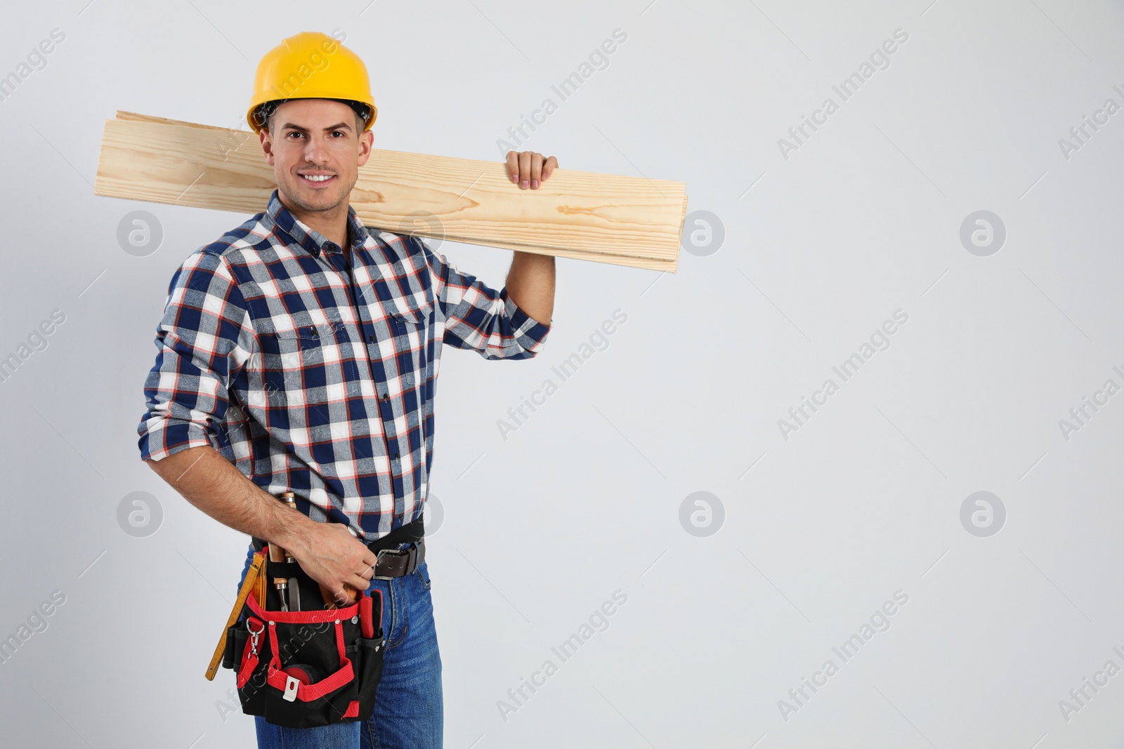 Photo of Handsome carpenter with wooden planks on light background. Space for text