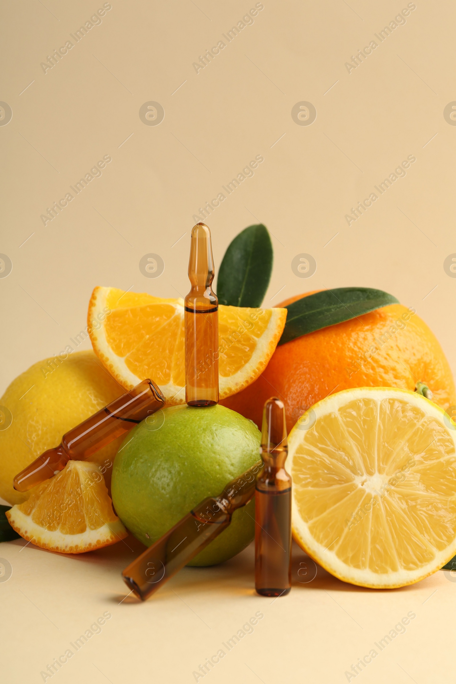 Photo of Skincare ampoules with vitamin C, different citrus fruits and leaves on beige background