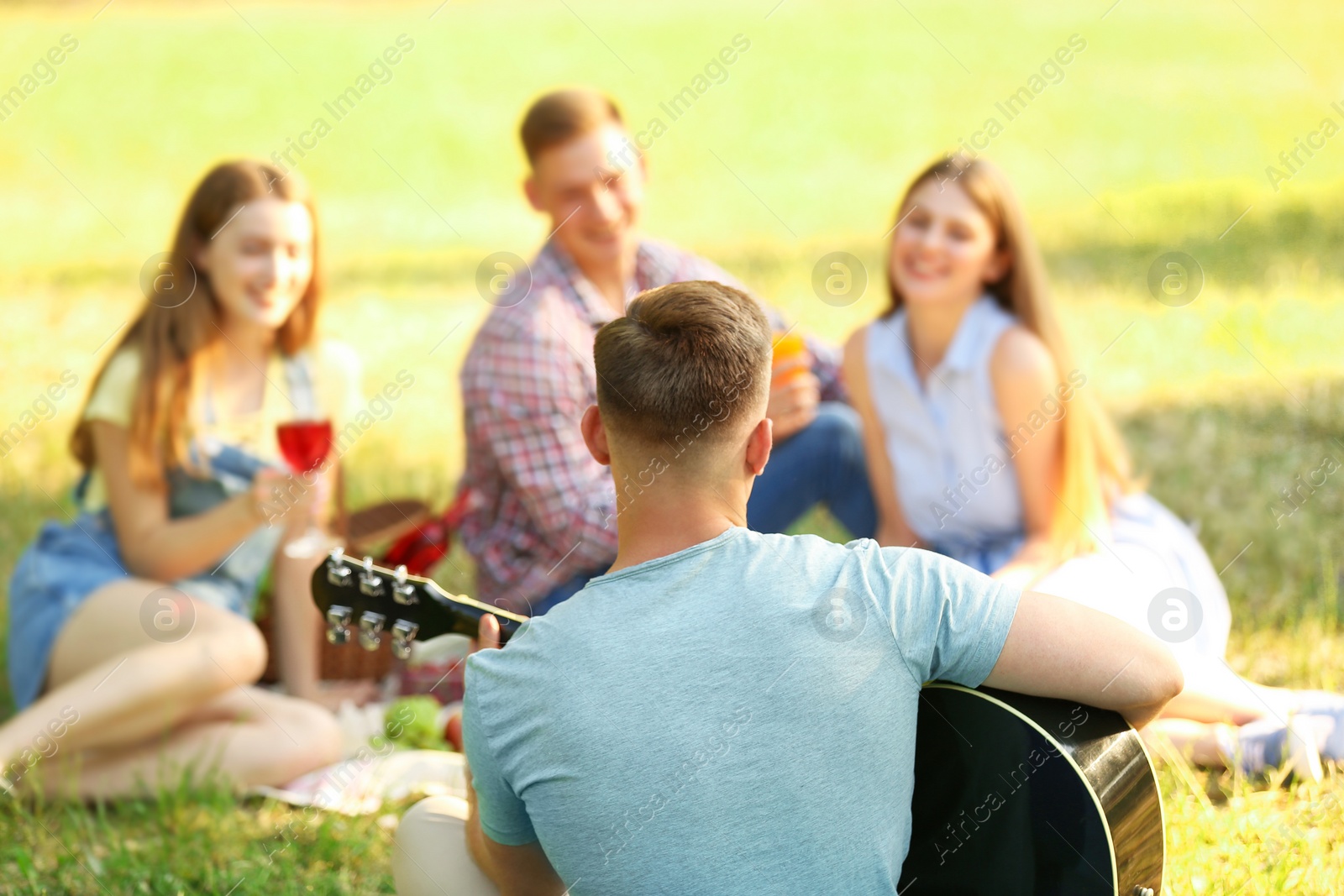 Photo of Young people enjoying picnic in park on summer day