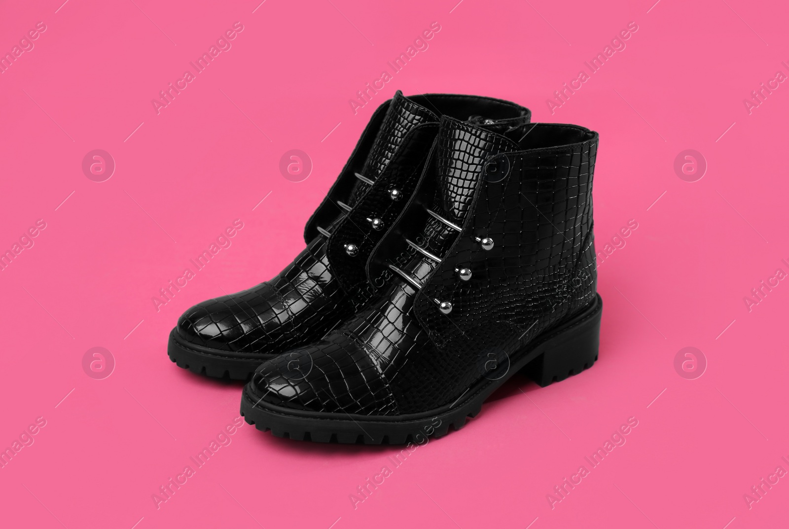 Photo of Pair of stylish ankle boots on pink background