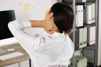 Young woman suffering from neck pain in office