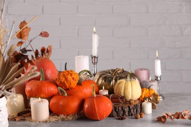 Photo of Beautiful composition with pumpkins and burning candles on table