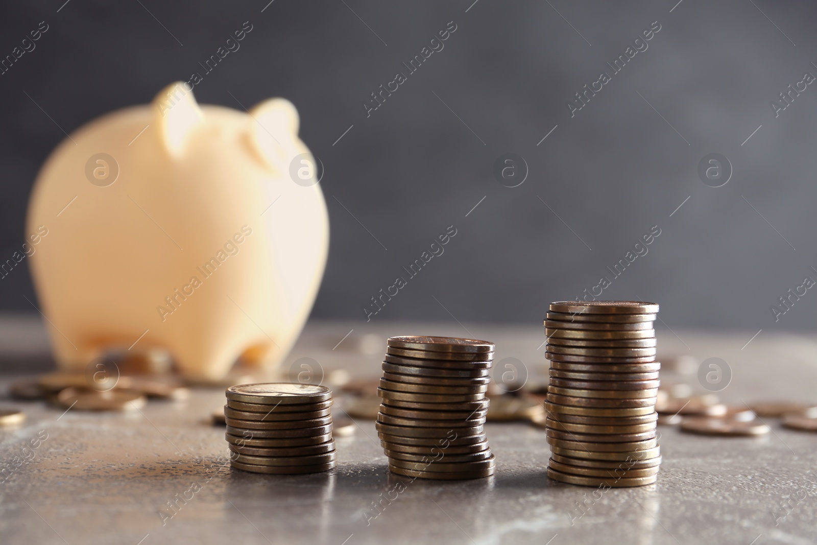 Photo of Stacked coins and piggy bank on brown marble table