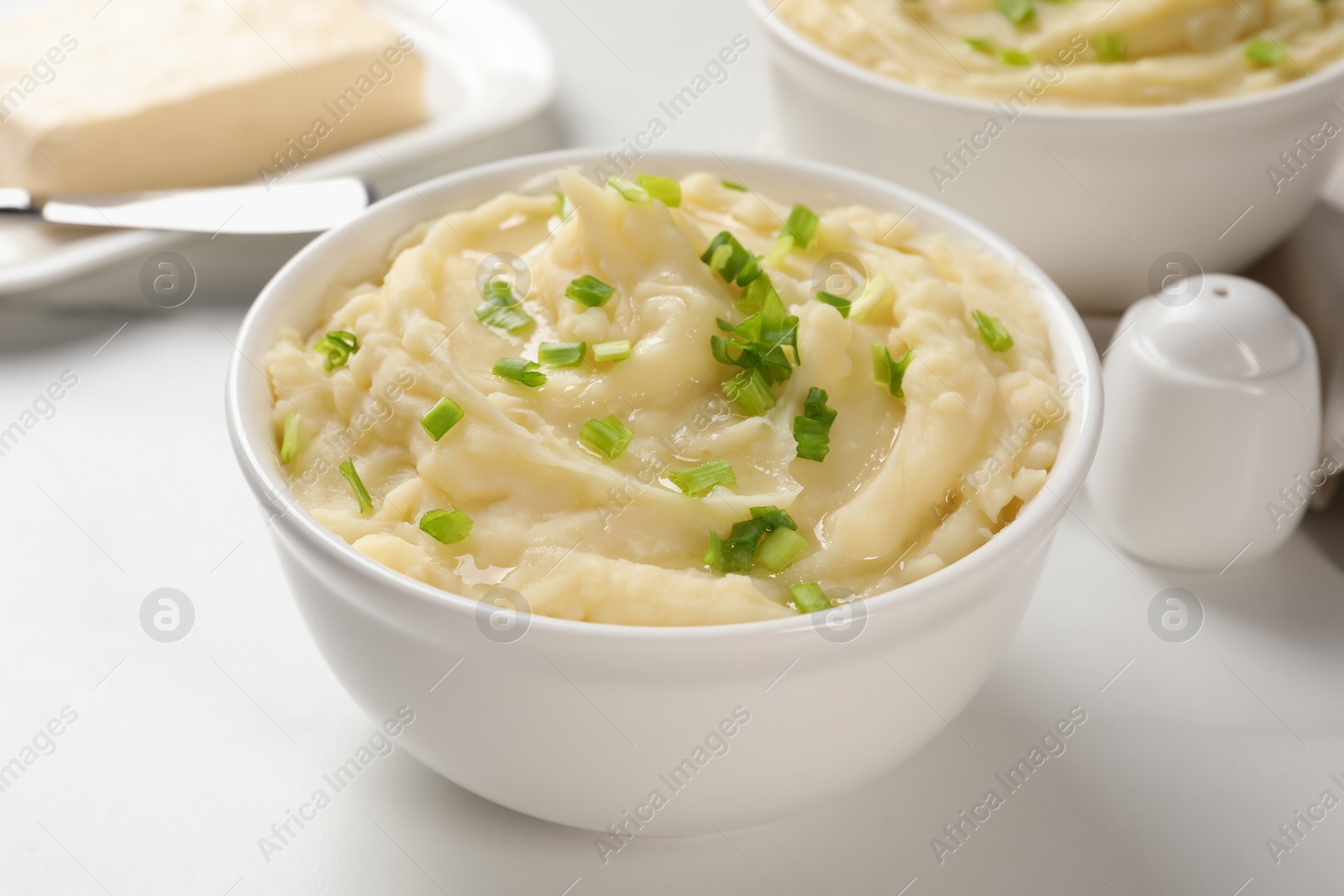 Photo of Bowls of delicious mashed potato with green onion on white table