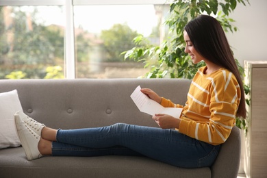 Photo of Woman reading letter on sofa at home