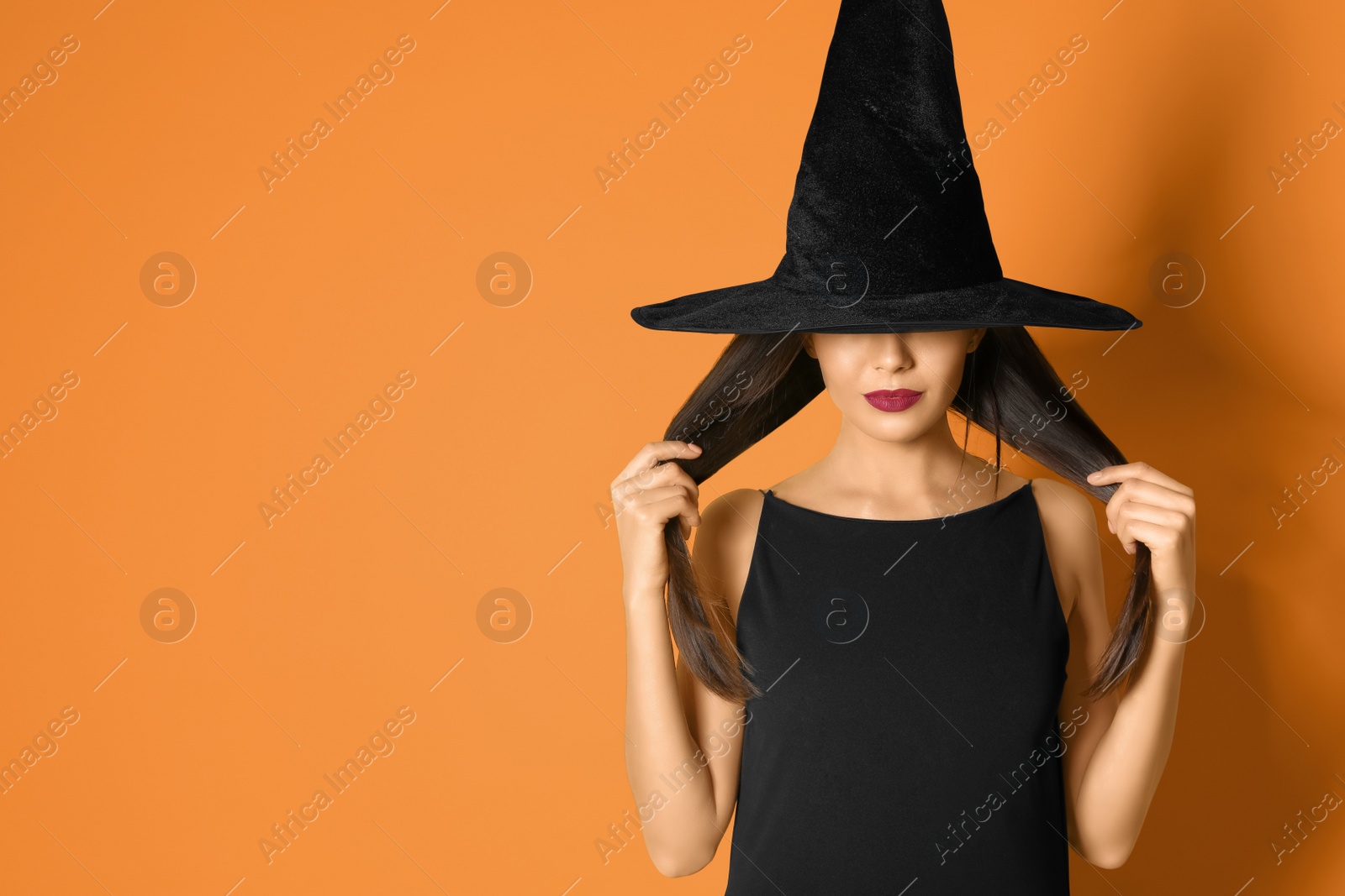 Photo of Beautiful woman wearing witch costume for Halloween party on yellow background, space for text