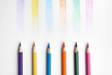 Photo of Colorful pencils with swatches on white background, top view