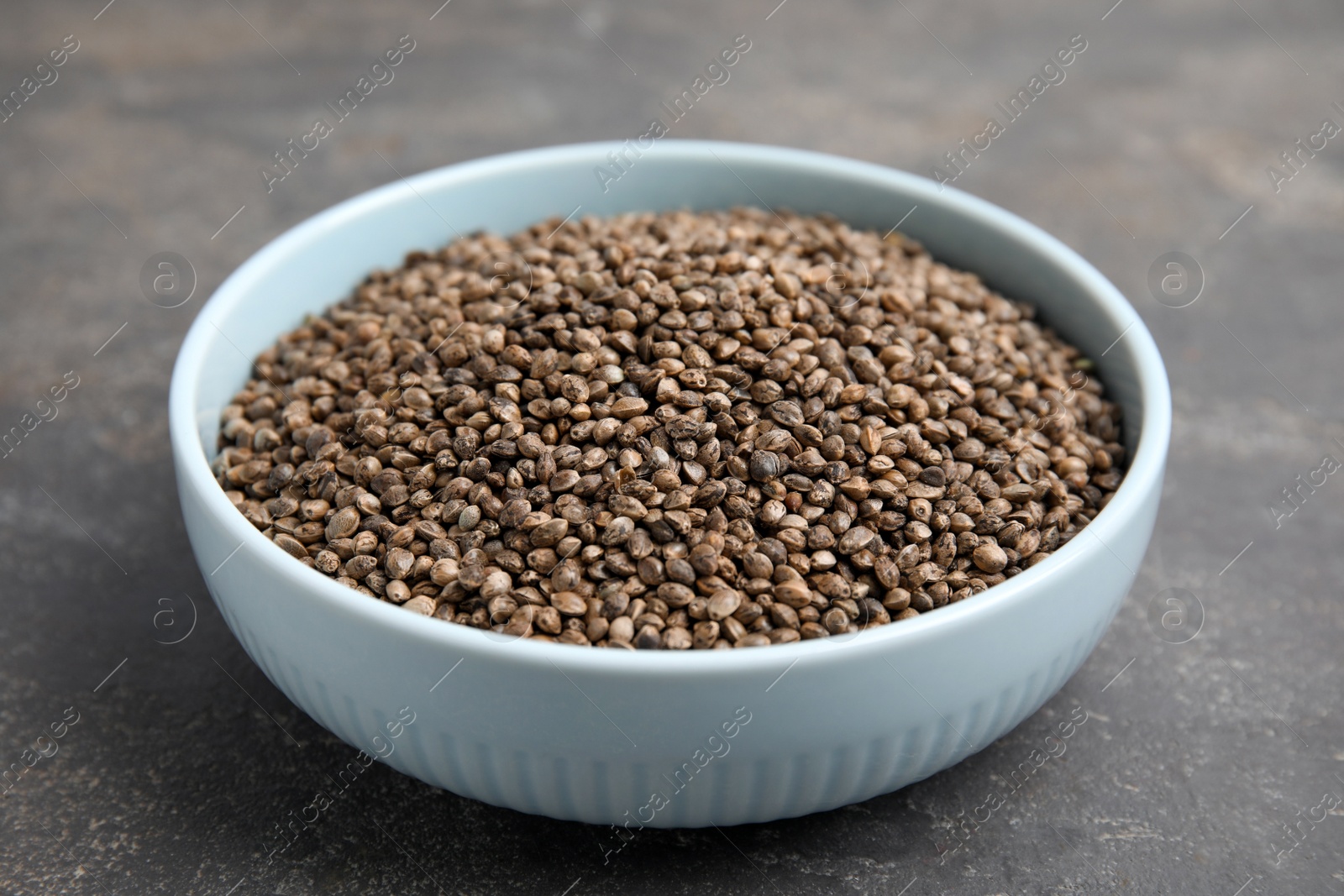 Photo of Bowl with hemp seeds on grey table