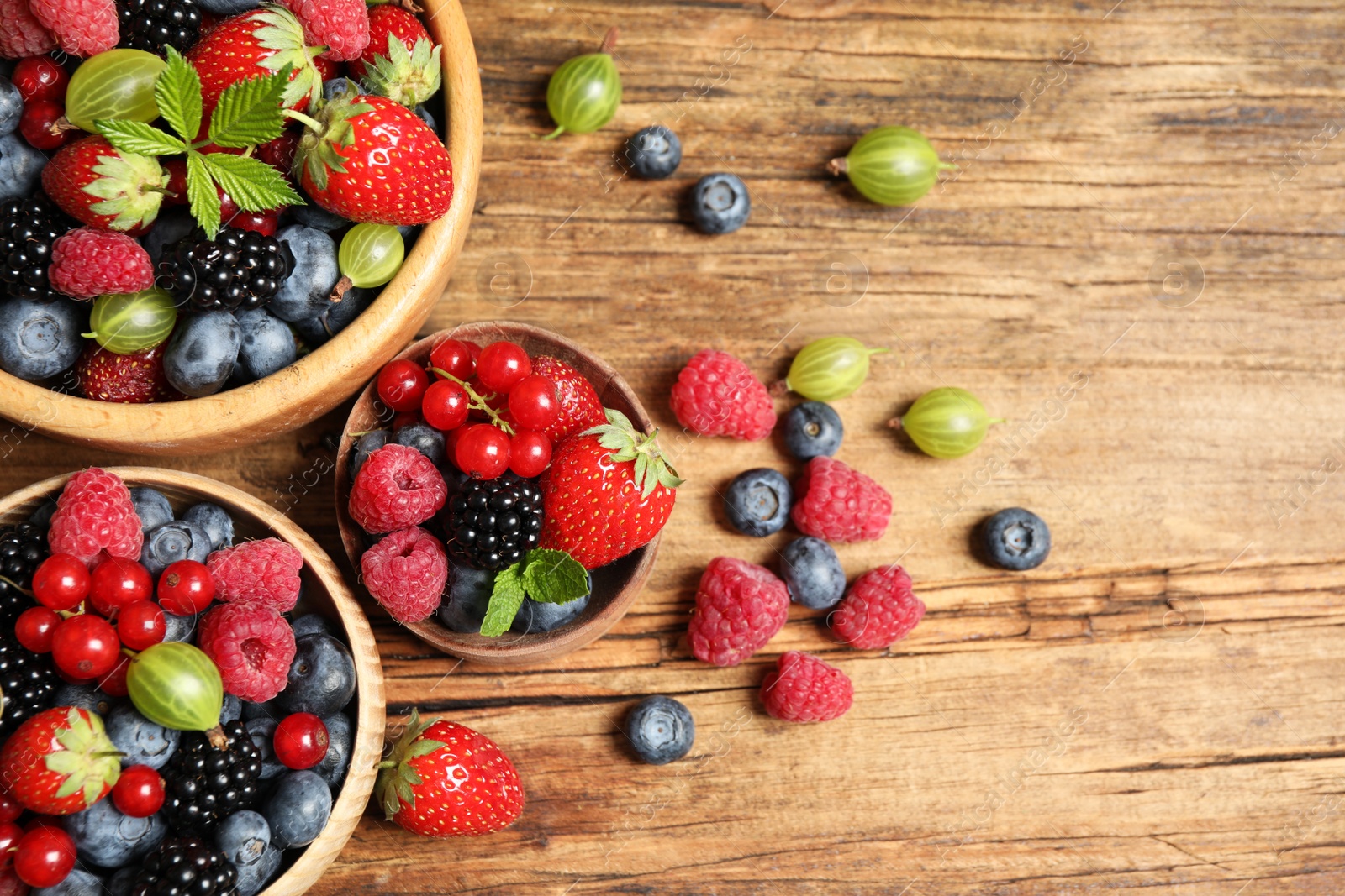 Photo of Mix of ripe berries on wooden table, flat lay