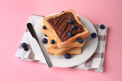 Photo of Tasty toast with chocolate paste and blueberries on pink table