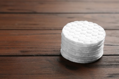 Photo of Stack of cotton pads on wooden background. Space for text