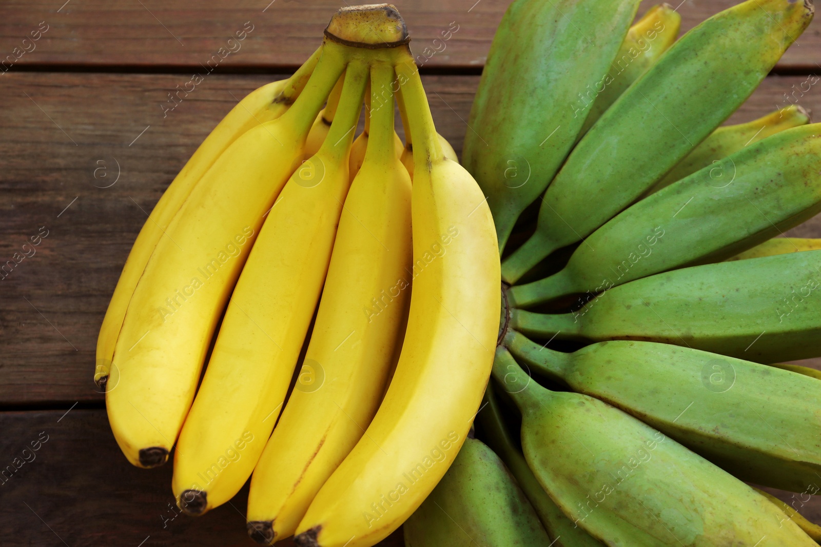 Photo of Bunches of tasty bananas on wooden table, flat lay