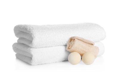 Photo of Stack of clean soft towels, bath bombs and sponge on white background