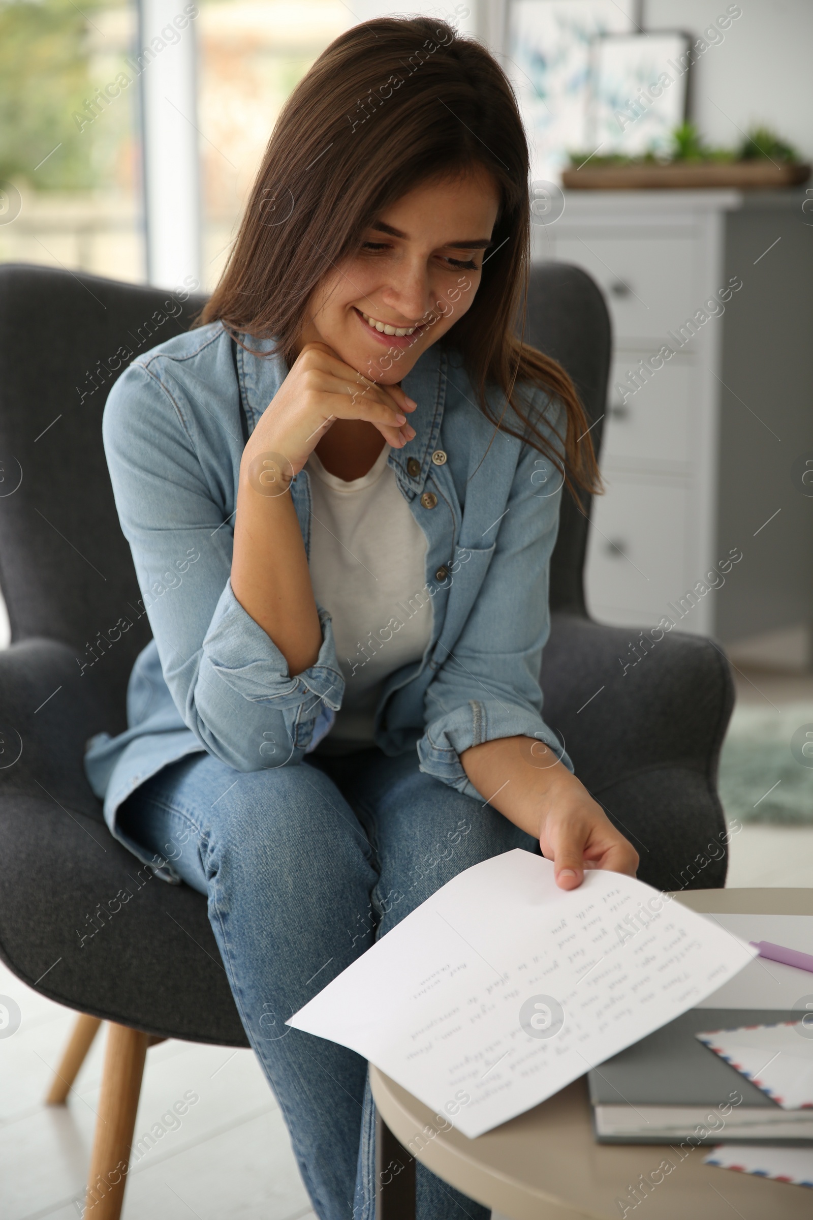 Photo of Young woman reading paper letter at home