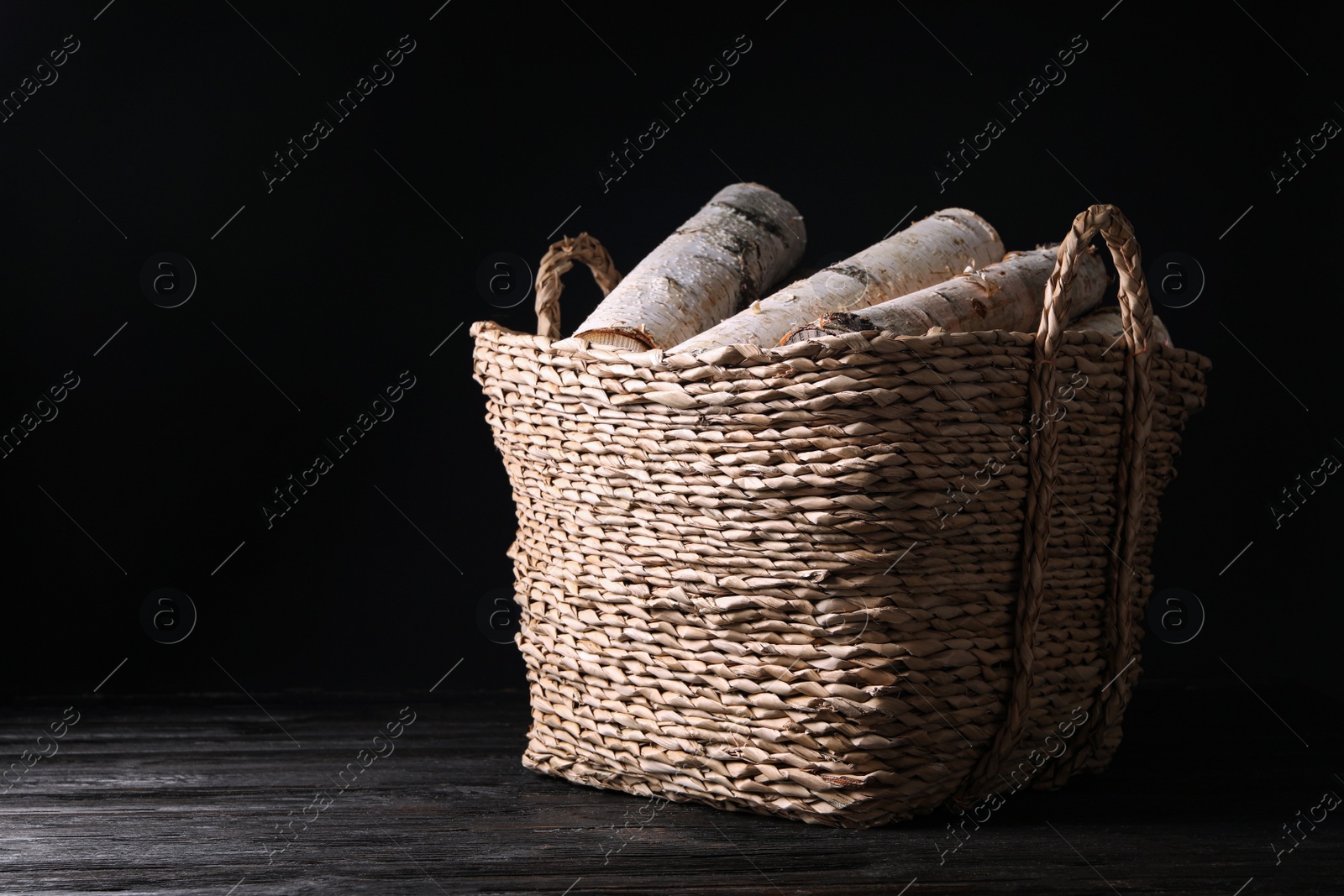 Photo of Cut firewood on table against black background