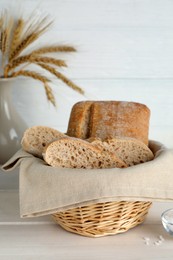 Cut delicious ciabatta in wicker basket on beige wooden table