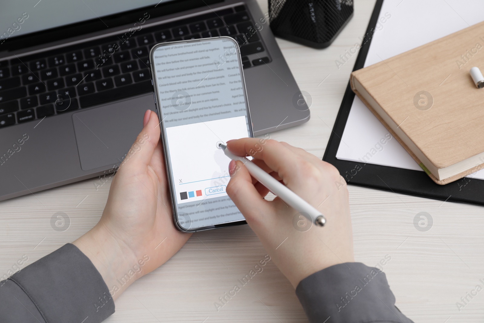 Image of Electronic signature. Woman using stylus and mobile phone at white wooden table, closeup