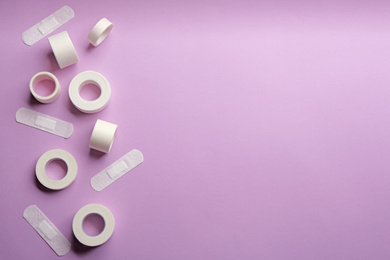 Photo of Different types of sticking plasters on lilac background, flat lay. Space for text