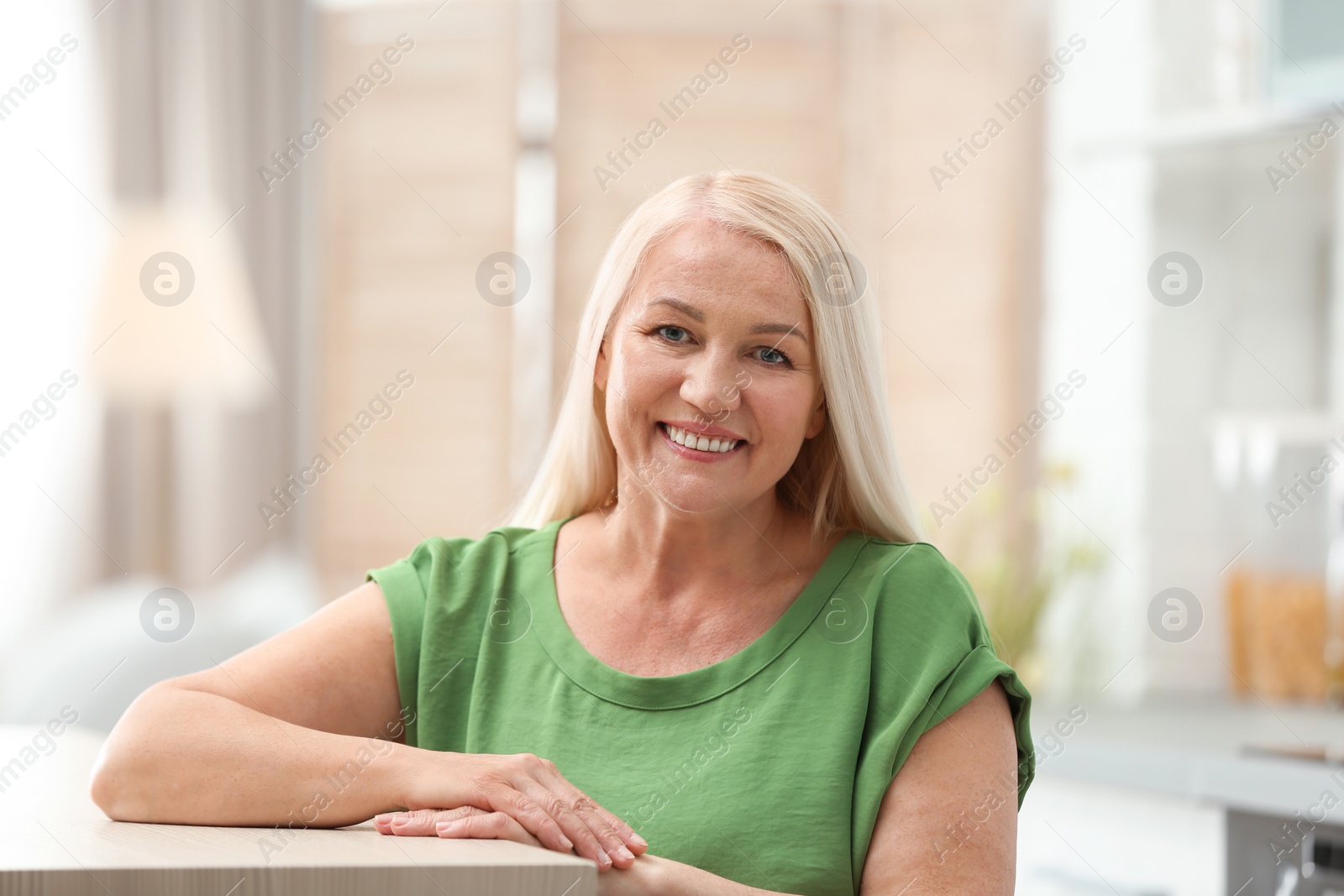 Photo of Portrait of happy mature woman at table indoors