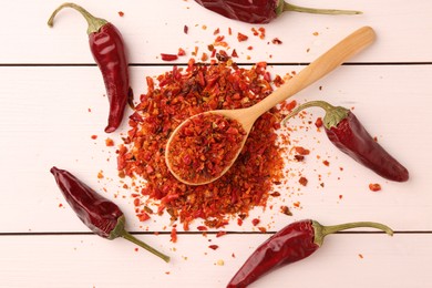 Photo of Chili pepper flakes and pods on white wooden table, flat lay