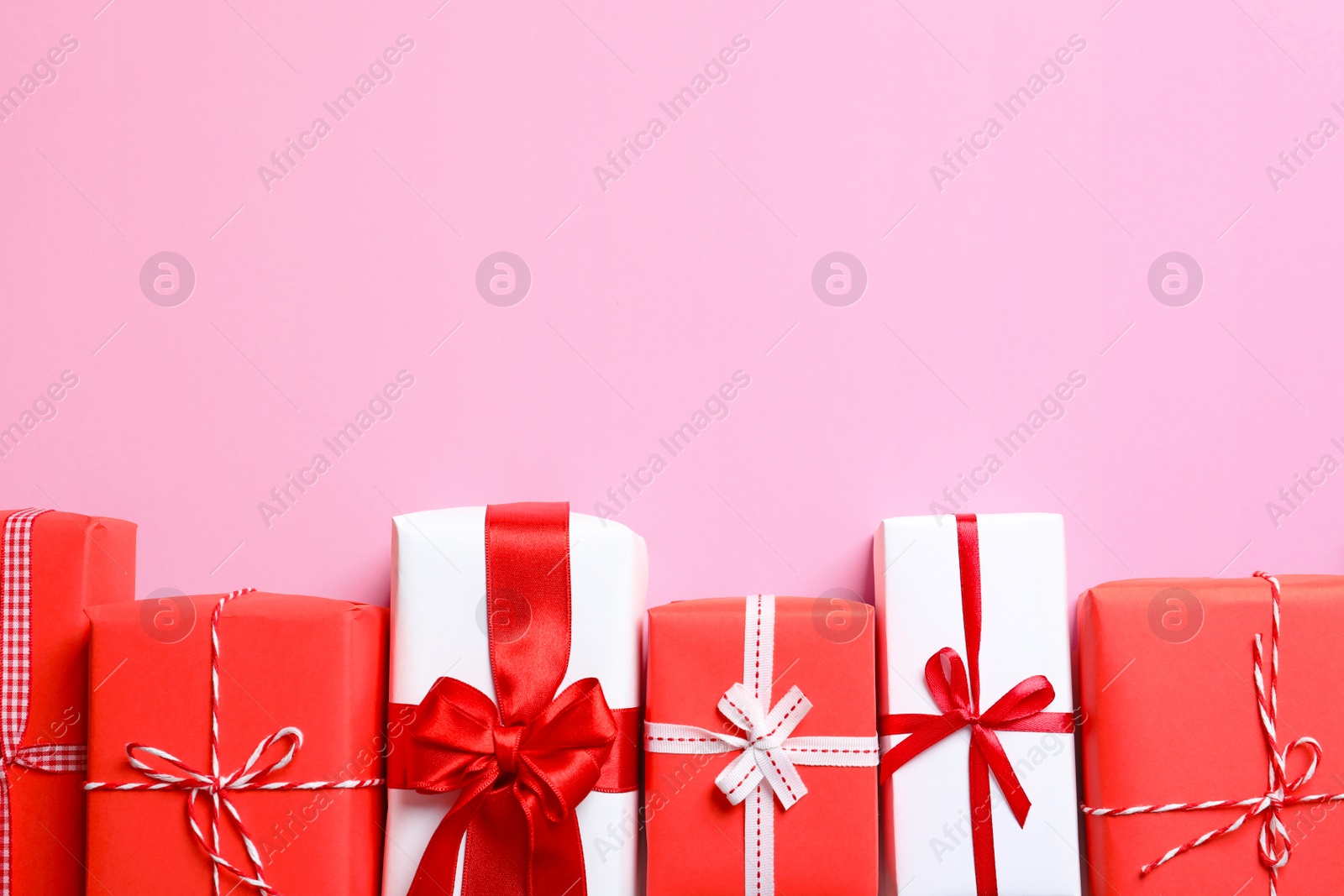 Photo of Beautifully wrapped gift boxes on color background, top view