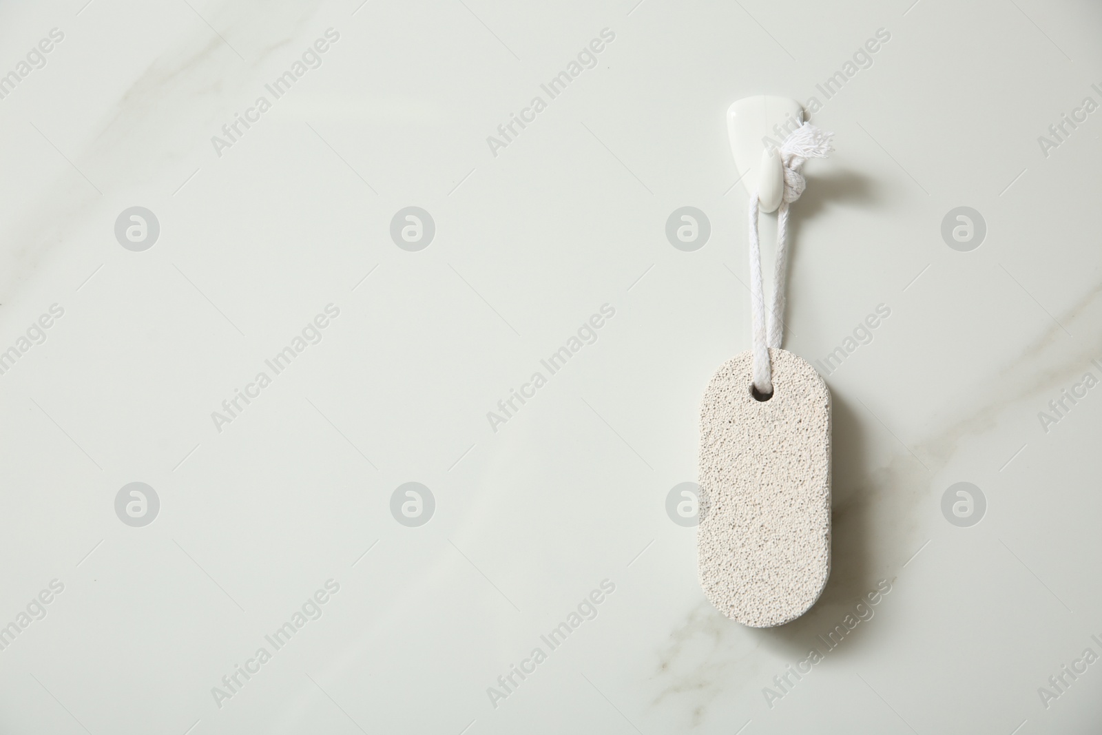 Photo of Pumice stone hanging on white wall, space for text