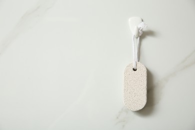 Pumice stone hanging on white wall, space for text