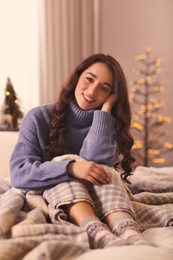 Young woman in knitted sweater resting at home. Winter atmosphere