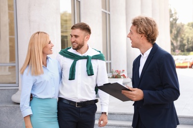 Photo of Male real estate agent with clients outdoors