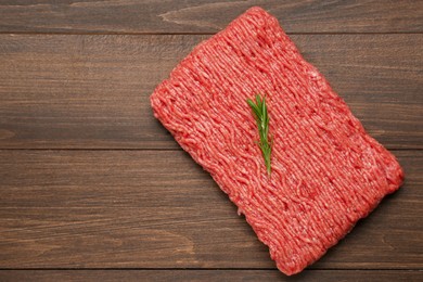 Photo of Raw fresh minced meat with rosemary on wooden table, top view. Space for text