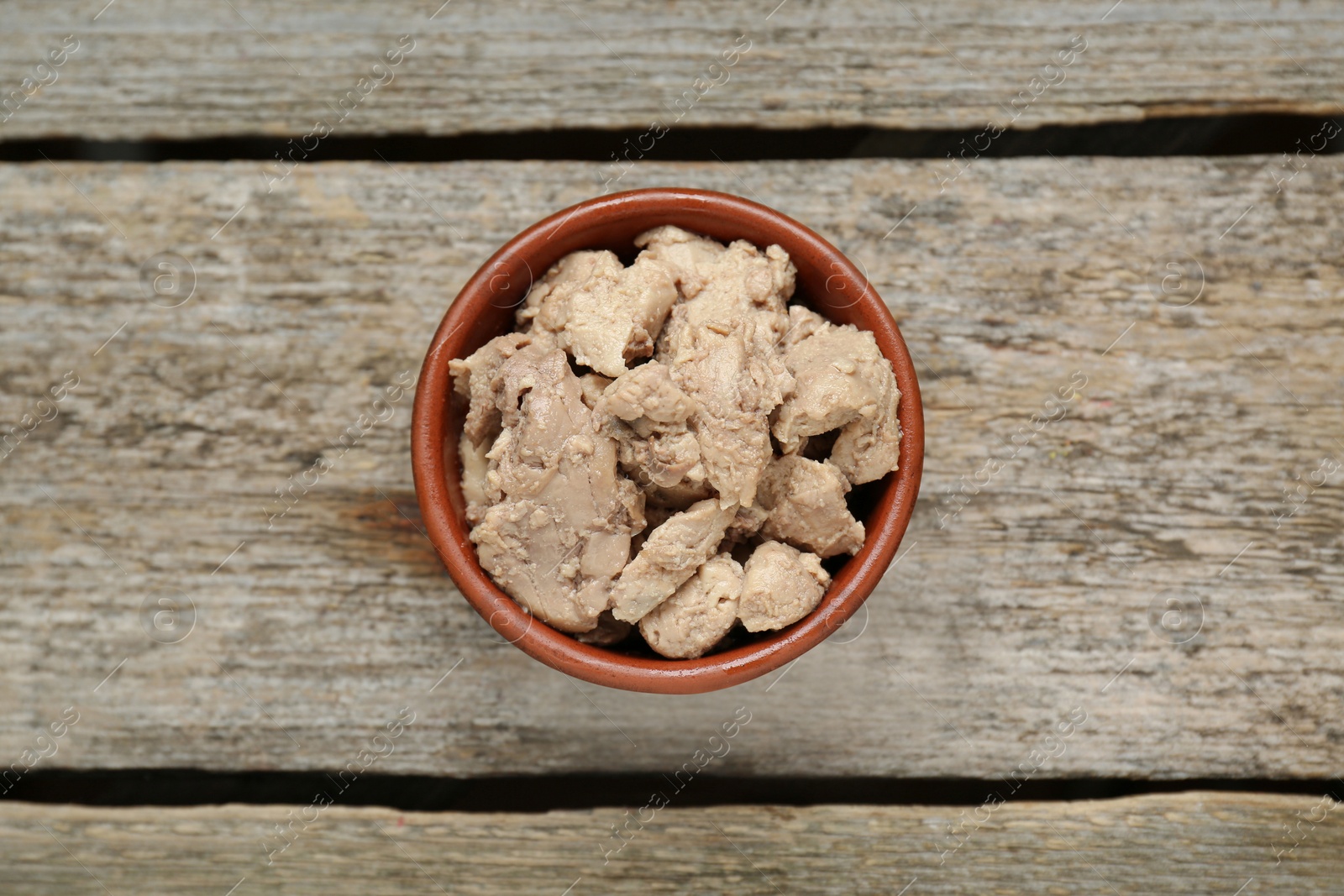 Photo of Bowl of tasty cod liver on wooden table, top view