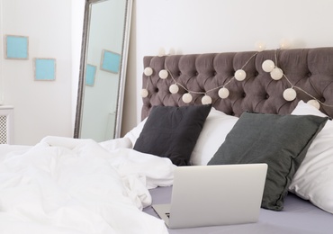 Photo of Laptop on bed in stylish room interior