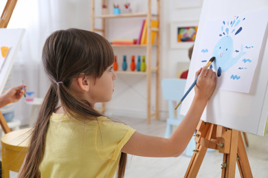 Cute little child painting during lesson in room