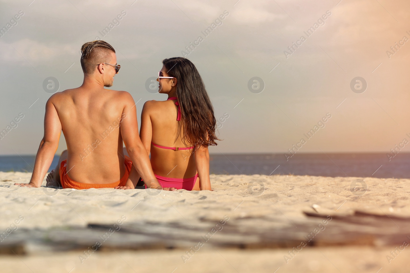 Photo of Young woman in bikini spending time with her boyfriend on beach. Lovely couple