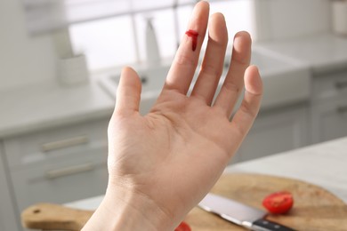 Woman cut finger while cooking in kitchen, closeup