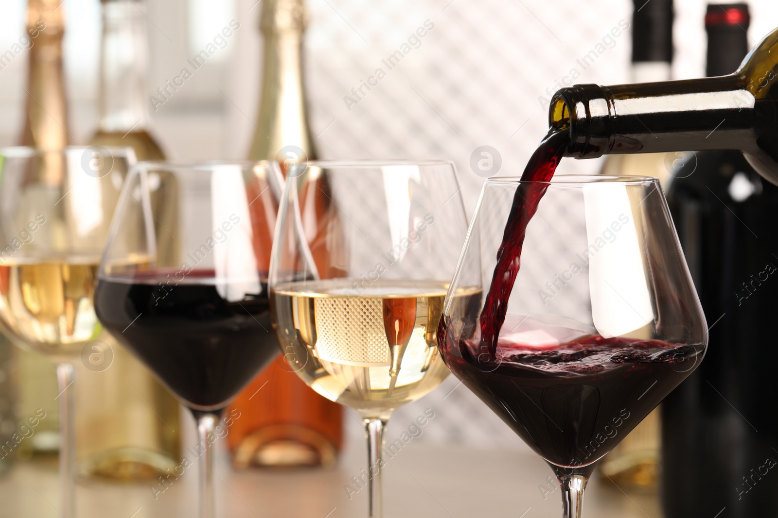 Photo of Pouring red wine from bottle into glass, closeup