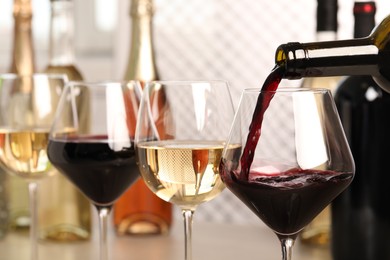 Photo of Pouring red wine from bottle into glass, closeup