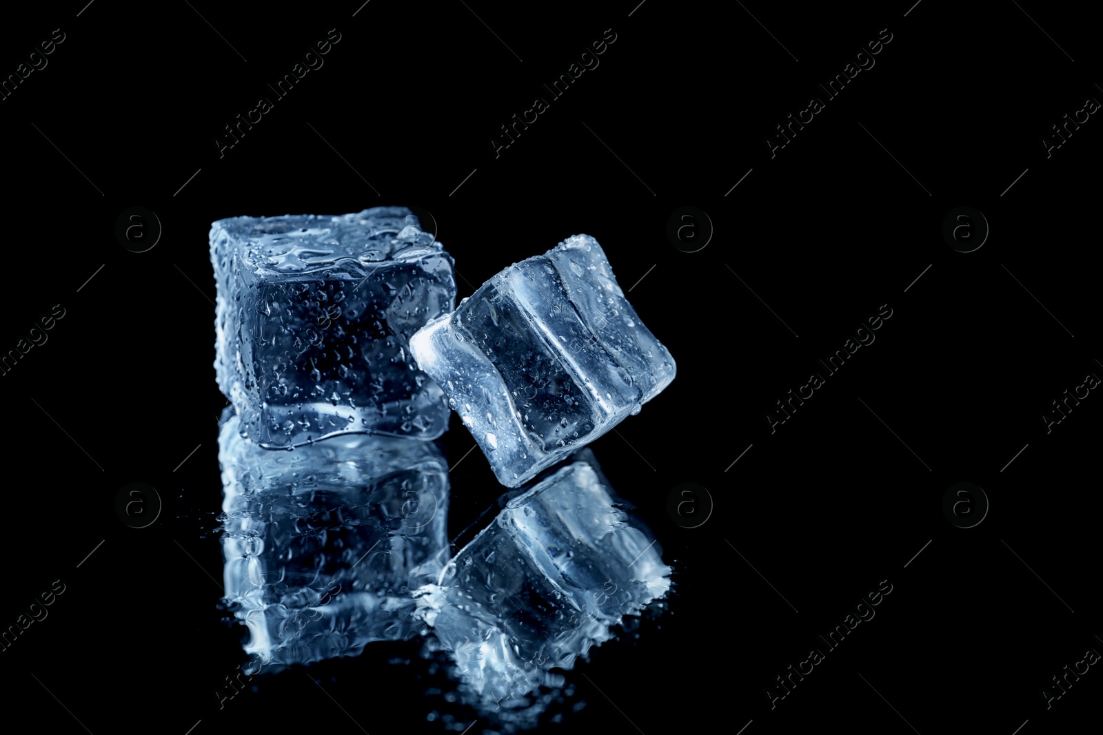 Photo of Ice cubes on black mirror surface. Space for text