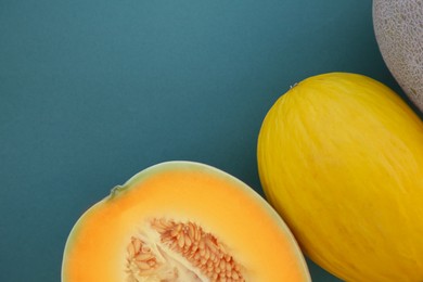 Different tasty ripe melons on teal background, flat lay. Space for text