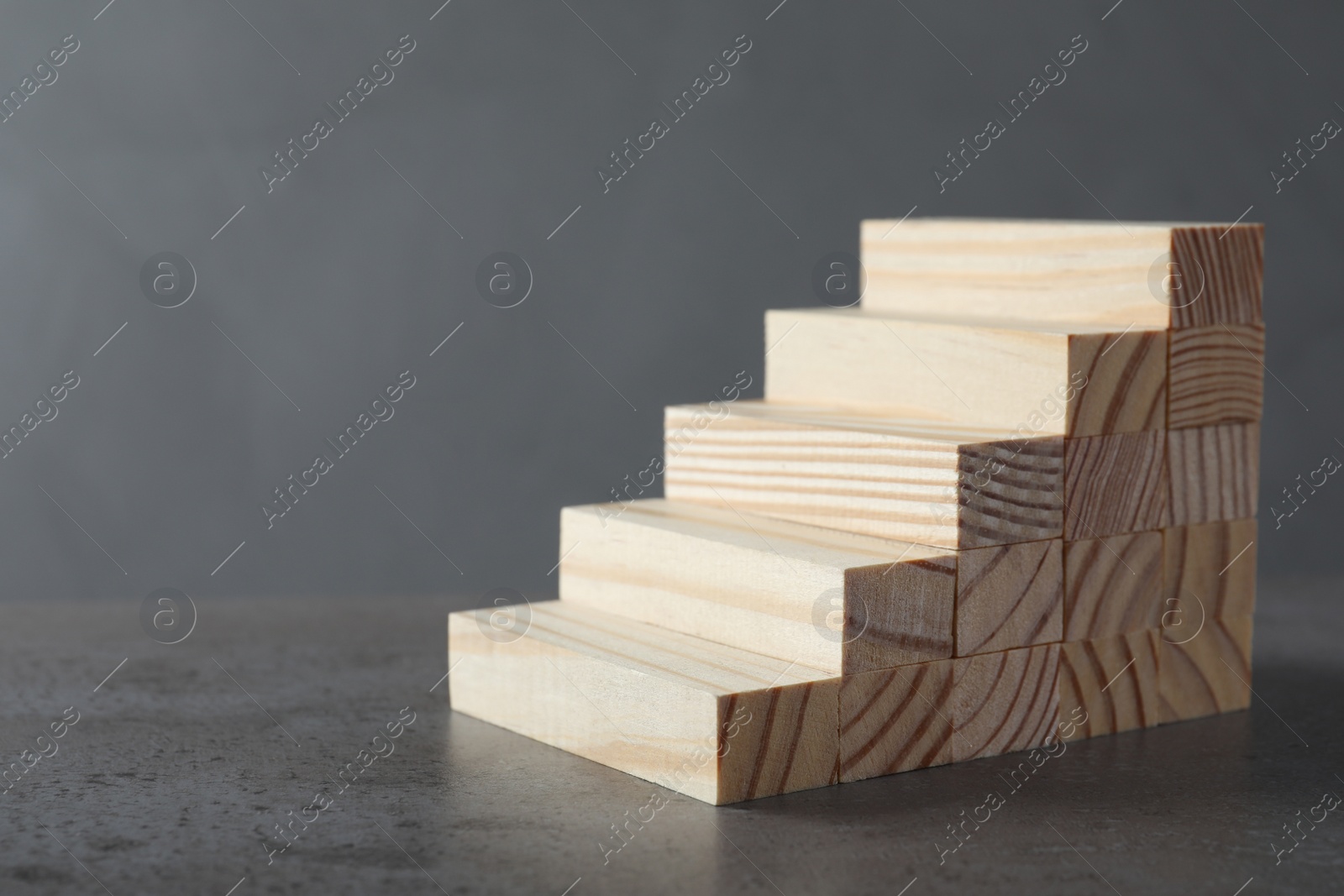 Photo of Steps made with wooden blocks on table against grey background, space for text. Career ladder