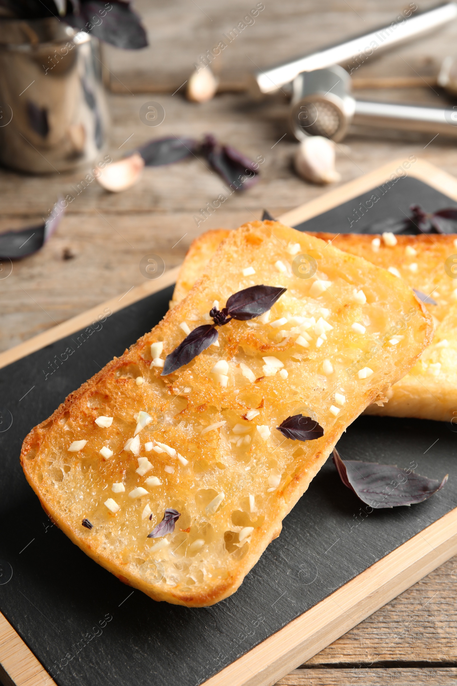 Photo of Board with delicious homemade garlic bread on table