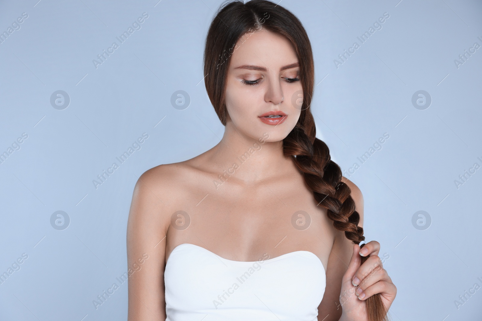 Photo of Young woman with strong healthy braided hair on light blue background